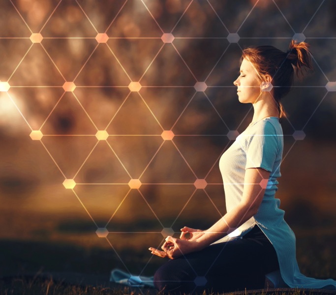 Woman meditating outdoors at sunset, with a glowing geometric pattern overlaying the scene.