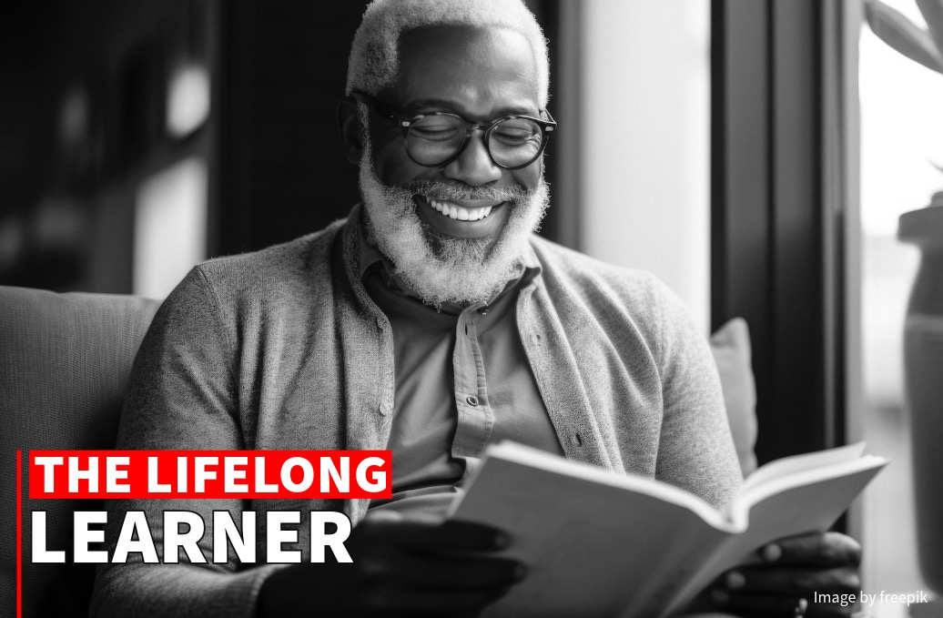 Elderly man with glasses smiling while reading a book in a cozy room, with "the lifelong learner" text overlay.